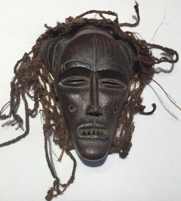 Chowke: Maske af udskåret og patinere træ, prydet med skæg af plantefibre, Congo ca. 1950. H. 23.